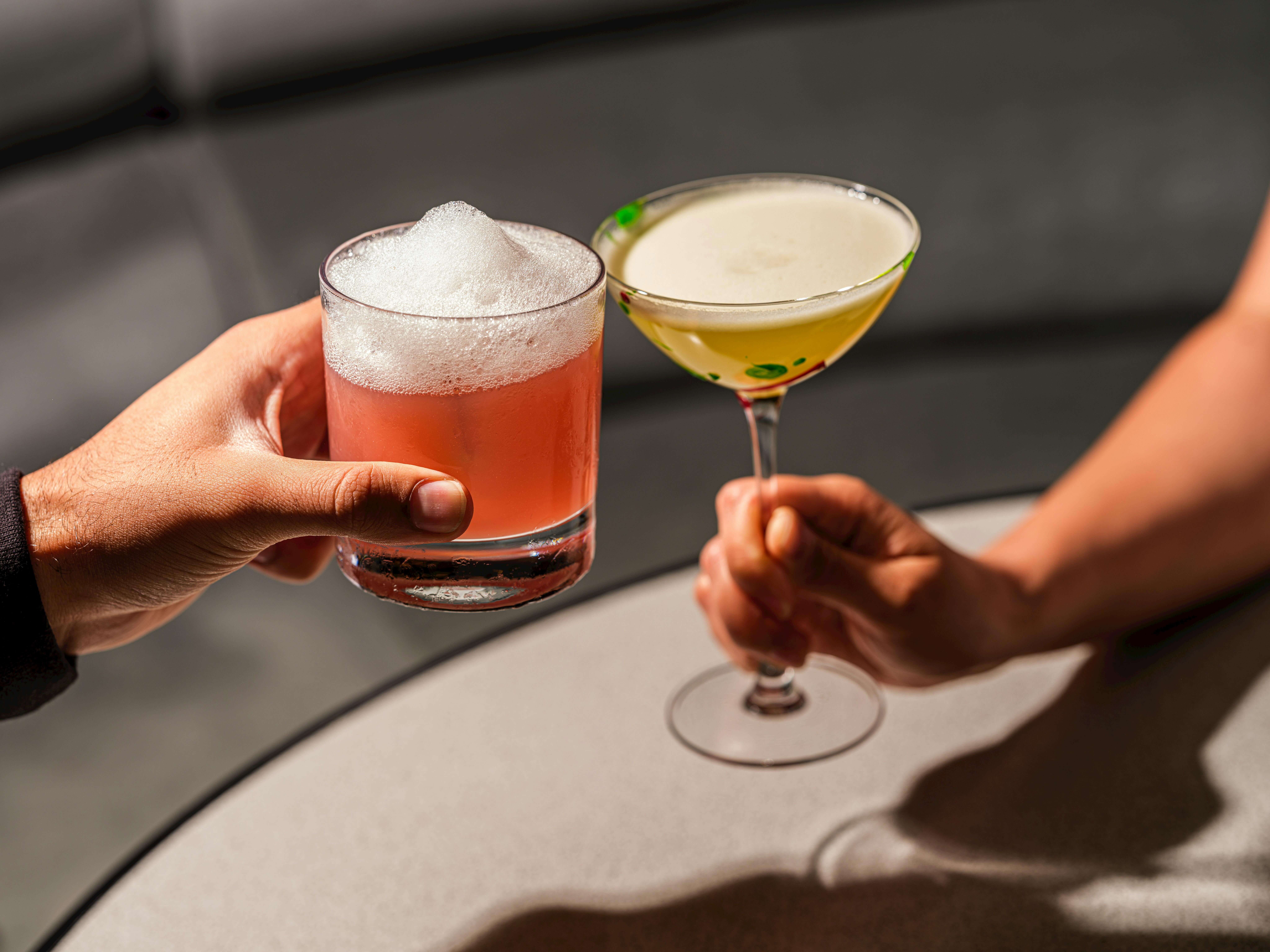 two people with cocktails clinking glasses