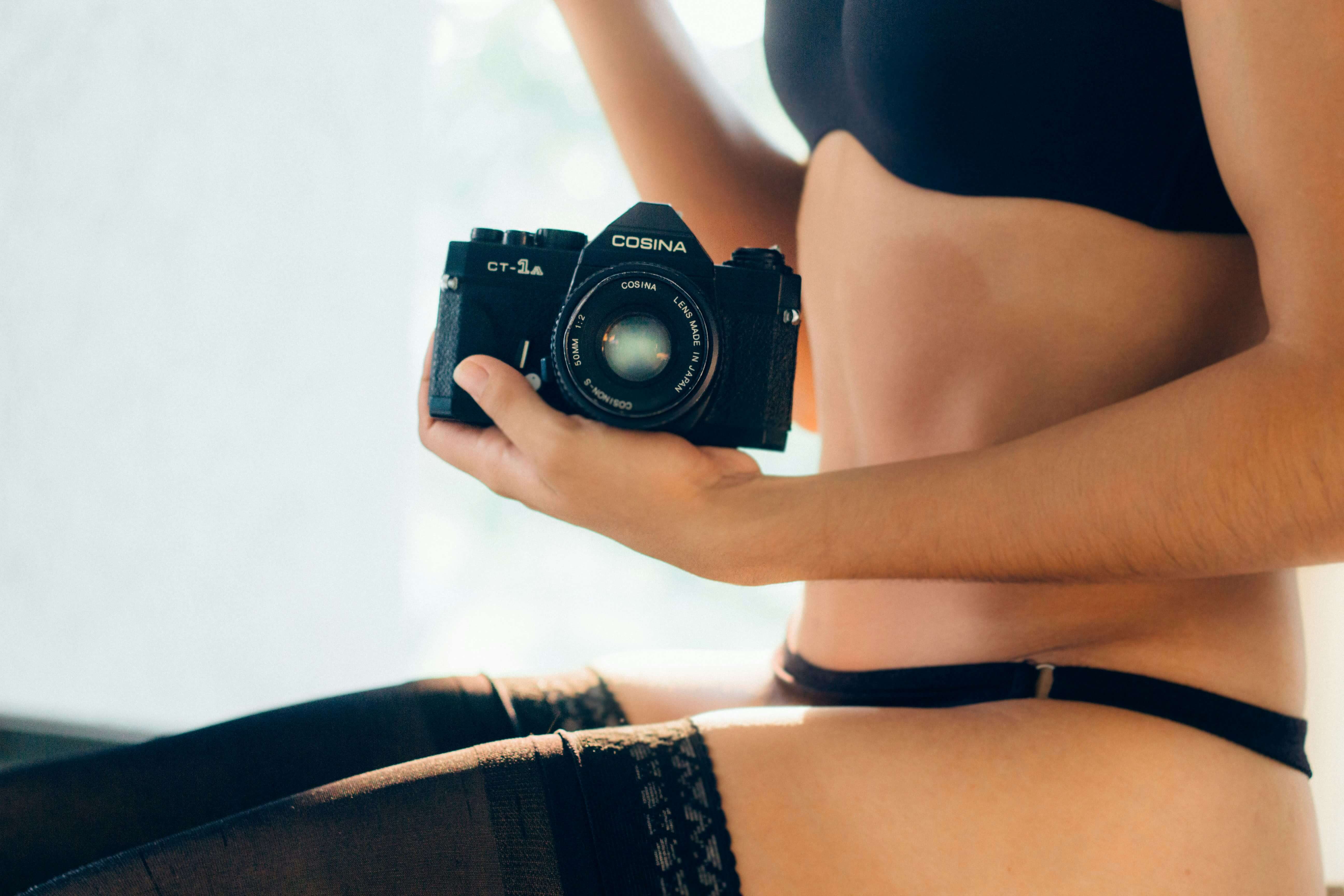 an escort in black lingerie holding a camera
