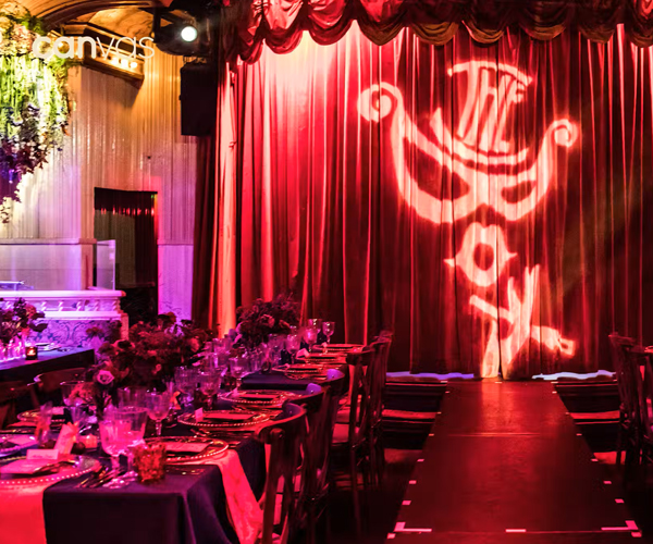 The curtain to the stage inside the box gentleman's club with the logo lit up